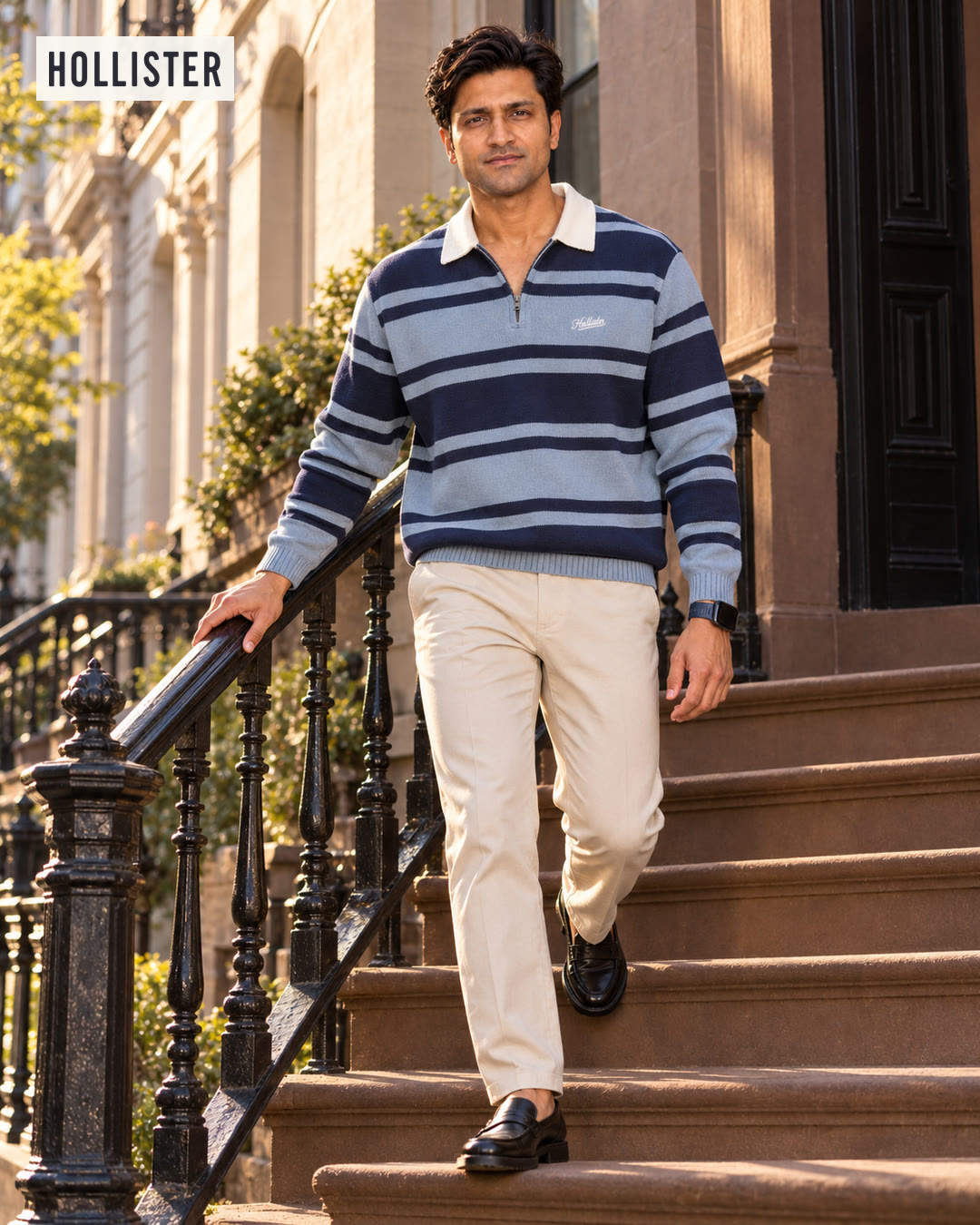 Man in a blue and navy striped zip polo sweater and cream trousers walking down brownstone steps.