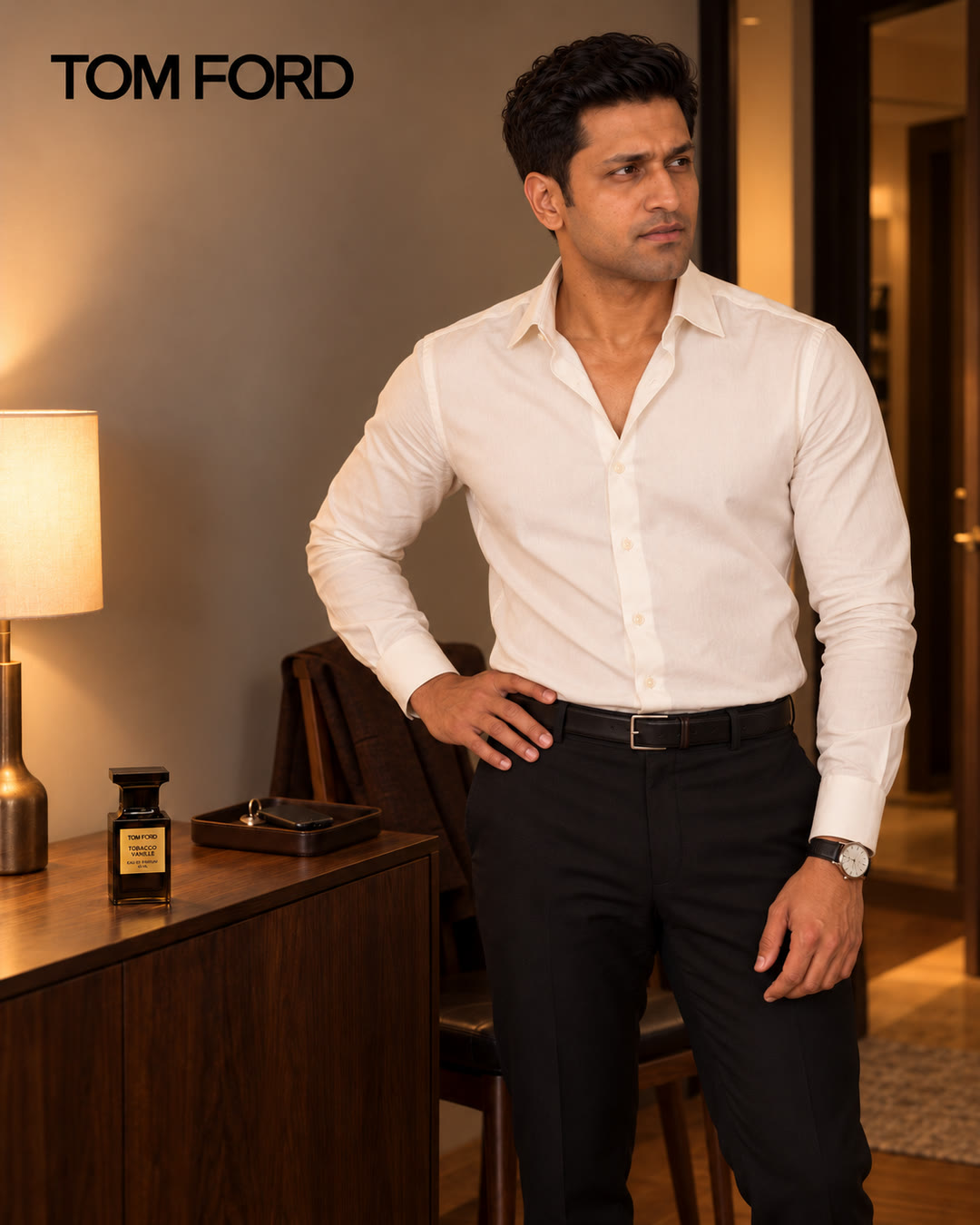 Man in a white shirt with one hand on his hip, glancing off to the side, the fragrance on the sideboard behind him.